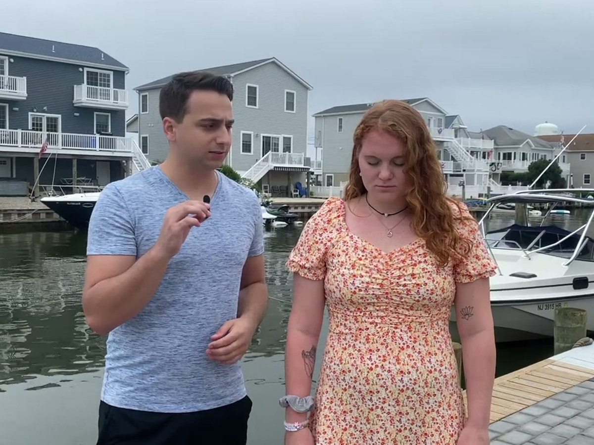 Tyler guiding a waterfront demonstration beside a participant with eyes closed and head slightly lowered.